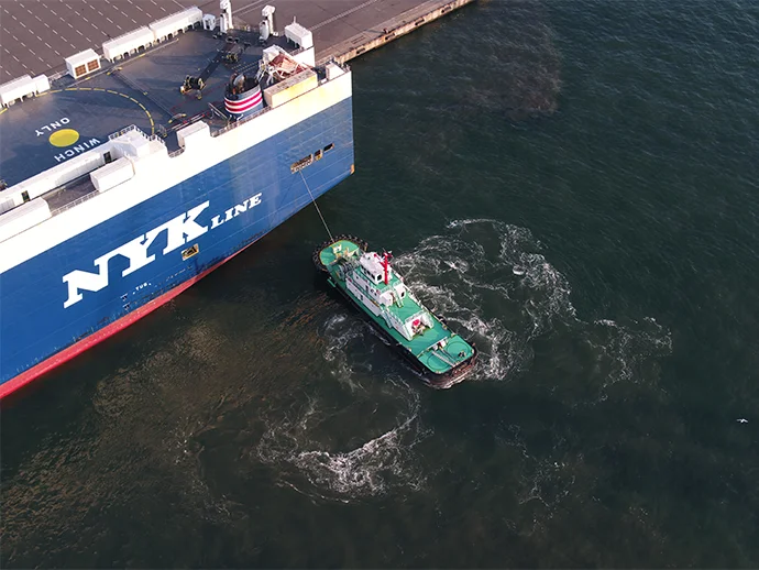 A tugboat assisting a car carrier 