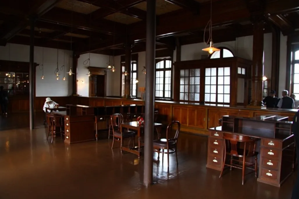 The former sales office just inside the main entrance, featuring beautifully polished wooden columns and capitals that showcase Meiji-era (1868–1912) craftsmanship. Some furniture still bears NYK equipment numbers from that time.